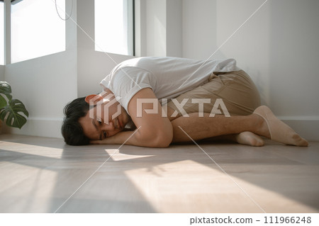 Sad and depressed man hugging himself down on the floor. 111966248