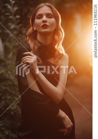 Elegant woman in black dress, sunset background. Elegant woman in black dress, sunset background. 111968216