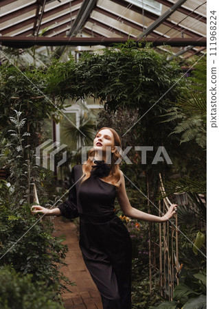 A woman walking through a greenhouse. A woman walking through a greenhouse. 111968224