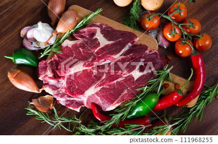 Pieces of fresh beef meat steaks on a wooden desk with vegetables and rosemary 111968255