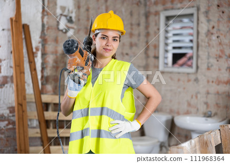 Female civil engineer holding pneumatic chipping hammer at construction site 111968364
