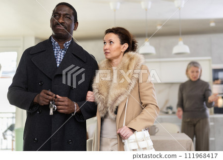 Middle-aged couple leaving the house while old woman quarreling to them 111968417