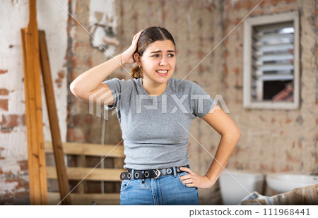 Confused young woman standing in her apartment during renovations Confused young woman standing in her apartment during renovations 111968441