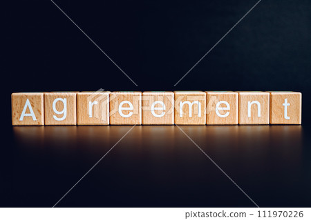 Wooden blocks form the text "Agreement" against a black background. Wooden blocks form the text "Agreement" against a black background. 111970226
