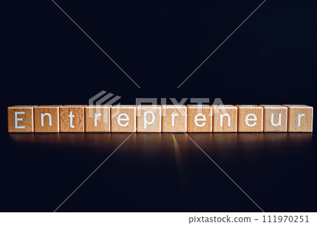 Wooden blocks form the text "Entrepreneur" against a black background. Wooden blocks form the text "Entrepreneur" against a black background. 111970251
