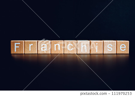 Wooden blocks form the text "Franchise" against a black background. Wooden blocks form the text "Franchise" against a black background. 111970253