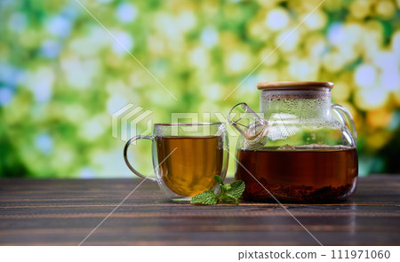 natural organic herbal tea in glass teapot and cup on a wooden table 111971060