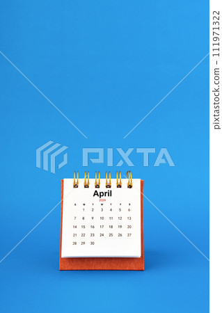 April 2024 white desk calendar on blue background. 111971322