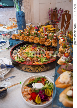 Delectable buffet spread of seafood, sushi, salads, fruit, and pastries. 111971591