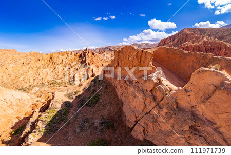 Aerial top view to beautiful landscape of Skazka canyon. Rocks Fairy Tale - famous destination in Kyrgyzstan. Rock formations in shape of a dragon spine like great wall of china on Issyk-Kul lake. Aerial top view to beautiful landscape of Skazka canyon. Rocks Fairy Tale - famous destination in Kyrgyzstan. Rock formations in shape of a dragon spine like great wall of china on Issyk-Kul lake. 111971739