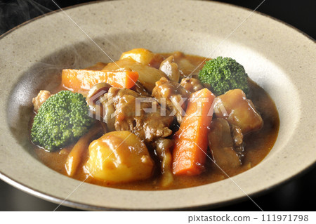 A photo of piping hot beef stew with many ingredients such as broccoli, carrots, and shimeji mushrooms against a black background. A photo of piping hot beef stew with many ingredients such as broccoli, carrots, and shimeji mushrooms against a black background. 111971798