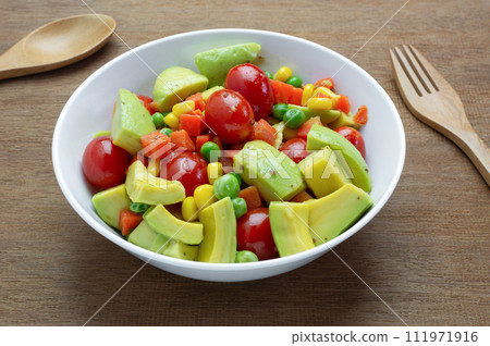 close up view of avocado salad with sesame soy sauce in a bowl on wooden table. homemade style healthy food concept. 111971916