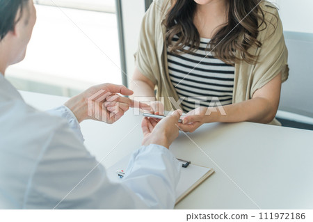 A woman receiving online medical treatment, smartphone examination, remote medical treatment, online examination, and medication guidance from a doctor on her smartphone. A woman receiving online medical treatment, smartphone examination, remote medical treatment, online examination, and medication guidance from a doctor on her smartphone. 111972186