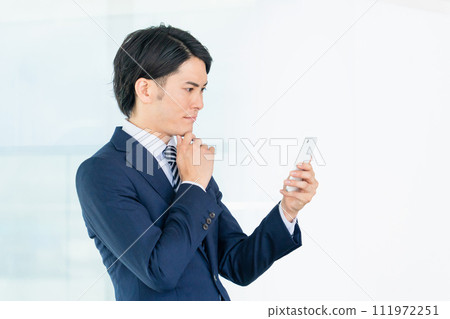 亞洲男性商人在辦公室看智慧型手機(思考、擔心、遇到麻煩、思考、考慮、想像) 亞洲男性商人在辦公室看智慧型手機(思考、擔心、遇到麻煩、思考、考慮、想像) 111972251