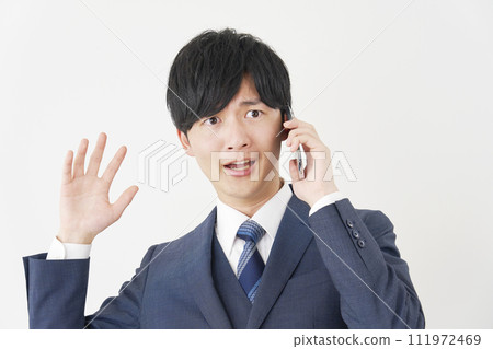 一位商人驚訝地打電話給他的智慧型手機，白色背景 111972469