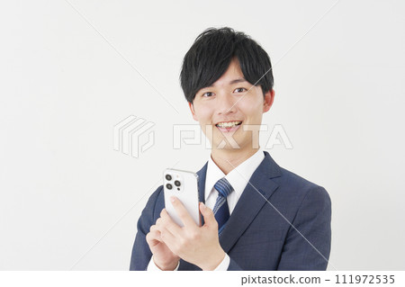 Businessman using smartphone, white background, looking at camera 111972535