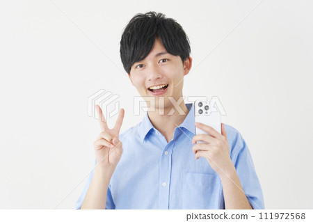 A man holding a smartphone and making a peace sign, white background 111972568