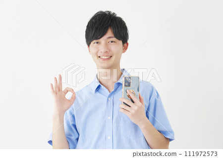 A man holding a smartphone and giving an OK sign, white background 111972573