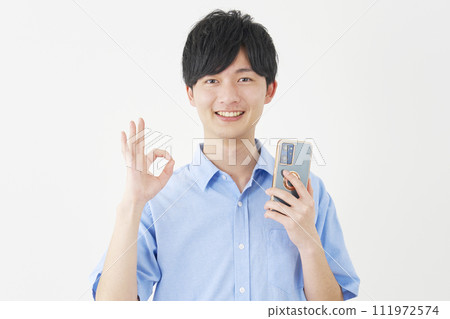 A man holding a smartphone and giving an OK sign, white background 111972574
