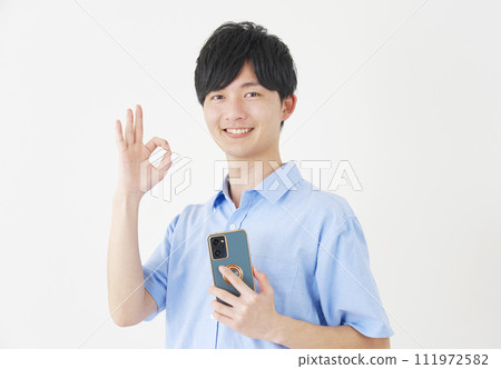 A man holding a smartphone and giving an OK sign, white background 111972582