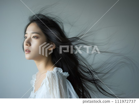 亞洲女人表情神秘,頭髮在風中舞動 亞洲女人表情神秘,頭髮在風中舞動 111972737