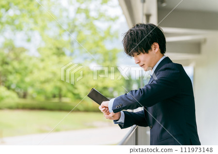 Young Asian businessman managing his schedule while looking at his watch (reporter/media/interview) Young Asian businessman managing his schedule while looking at his watch (reporter/media/interview) 111973148