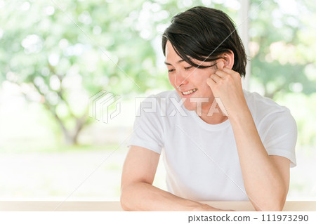A refreshing man in a white T-shirt on a background of fresh greenery (men's esthetics, men's beauty, men's beauty) 111973290