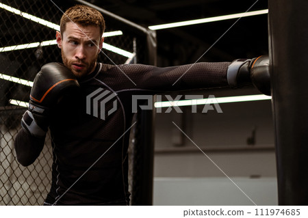 Concentrated boxer honing punching skills on heavy bag in gym Concentrated boxer honing punching skills on heavy bag in gym 111974685