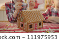 Cute boys decorating gingerbread house with topping and icing at the kitchen 111975953