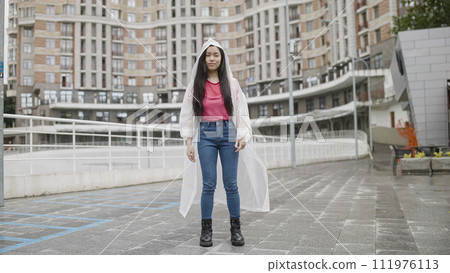 Young stylish Vietnamese woman standing under rain in the city, pop culture and youth 111976113