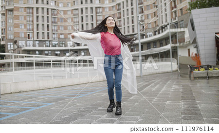 Happy beautiful asian woman in raincoat jumping and dancing on street, freedom 111976114