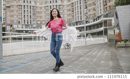Beautiful asian female student in white raincoat dancing on street, celebration 111976115