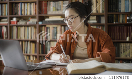 Tired woman asian student taking notes from online course, distance education 111976178