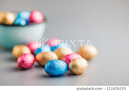 Easter chocolate eggs wrapped in aluminium foil on gray background. 111976235