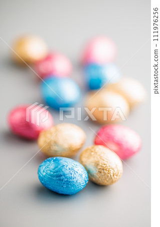 Easter chocolate eggs wrapped in aluminium foil on gray background. Easter chocolate eggs wrapped in aluminium foil on gray background. 111976256