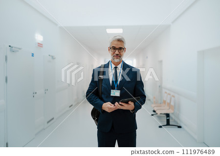Portrait of pharmaceutical sales representative in medical building, waiting for doctor, presenting new pharmaceutical product. Smiling drug rep standing in hall holding tablet. 111976489