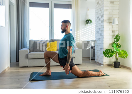 Handsome man doing yoga, stretching, resting after home workout, New Year's resolutions, exercising as healthy lifestyle and selfcare. Handsome man doing yoga, stretching, resting after home workout, New Year's resolutions, exercising as healthy lifestyle and selfcare. 111976560