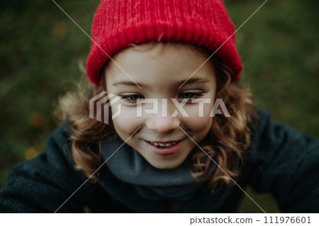 Portrait of little girl in red knitted hat. Red riding hood girl, little redcap lookalike. Portrait of little girl in red knitted hat. Red riding hood girl, little redcap lookalike. 111976601