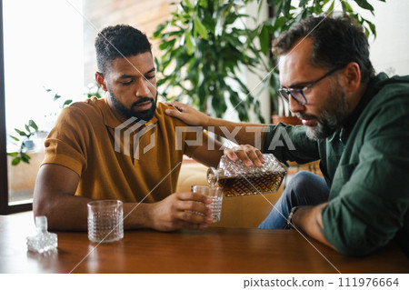 Best friends, supporting each other, drinking whiskey and talking. Discussing problems and drowning sorrows in alcohol. Concept of male friendship, bromance. Best friends, supporting each other, drinking whiskey and talking. Discussing problems and drowning sorrows in alcohol. Concept of male friendship, bromance. 111976664