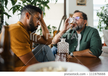 Best friends, supporting each other, drinking whiskey and talking. Discussing problems and drowning sorrows in alcohol. Concept of male friendship, bromance. 111976666