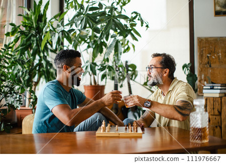Best friends playing chess together, drinking whiskey and talking. Concept of male friendship, bromance. 111976667