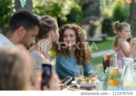 Portrait of couple sitting at the table with family and friends at the family garden party. Portrait of couple sitting at the table with family and friends at the family garden party. 111976704