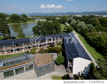Aerial view of solar panels on a rooftop of hotel complex. Solar energy as renewable energy source in business. Aerial view of solar panels on a rooftop of hotel complex. Solar energy as renewable energy source in business. 111976722