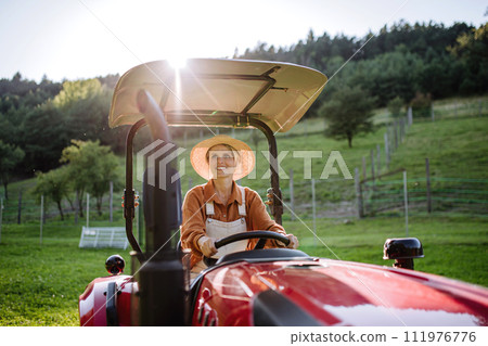 Progressive female farmer driving tractor on her own farm. Progressive female farmer driving tractor on her own farm. 111976776