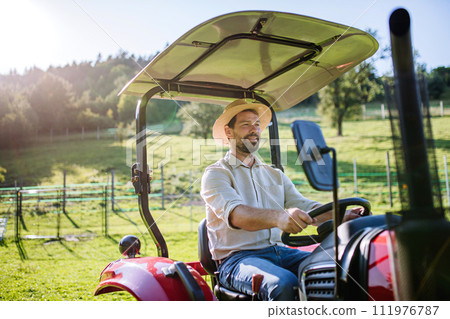 Farmer riding tractor on field. Harvesting crops, collecting vegetables on family farm. Concept of farming, agricultural business. Farmer riding tractor on field. Harvesting crops, collecting vegetables on family farm. Concept of farming, agricultural business. 111976787