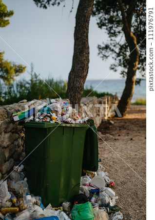 Trash in the street spilling on to the pavement. Full bins in holiday destinations. 111976791