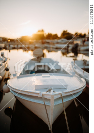 Small boats on calm water, moored in the harbor during sunset. 111976811