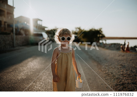 Portrait of blonde girl in summer outfit on walk during summer vacation, concept of beach holiday. 111976832