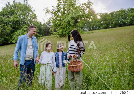 Family on interesting walk in forest, going through meadow. Mushroom, herbs medical plants or flowers picking, foraging. Concept of family ecological hobby in nature. 111976844