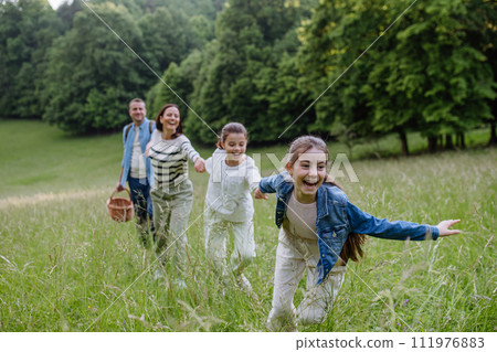 Family on interesting walk in forest, going through meadow. Mushroom, herbs medical plants or flowers picking, foraging. Concept of family ecological hobby in nature. 111976883